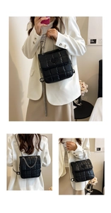 Detail of black quilted shoulder bag featuring silver chain and heart embossed logo