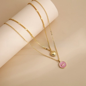 Detail of 18K gold-plated layered necklace with pink enamel disc and heart pendant