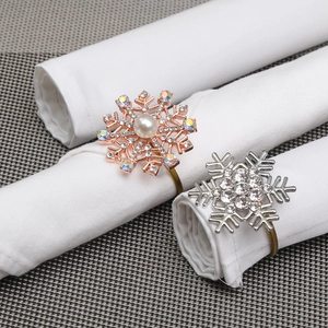 Detail of snowflake napkin rings with colorful rhinestones and pearls on white napkins