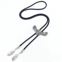 Detail of vintage silver eagle bolo tie with feather pendants and braided leather cord