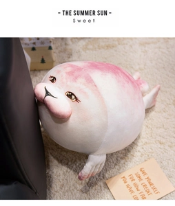 Close-up of a soft round plush seal doll with a pink gradient on a dark sofa