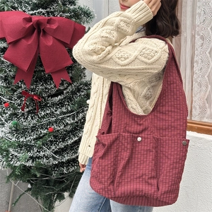 Detailed view of red plaid tote bag with external pockets and silver metal buckle decor