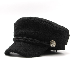 Detail of black faux shearling newsboy cap featuring braided rope and metallic button