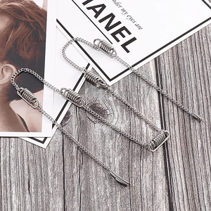 Close-up of silver spring-style earrings with delicate chains on a wooden background