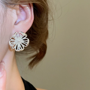 Nahaufnahme von minimalistischen silbernen hohlen Blumenohrringen am Modell für Schmuck