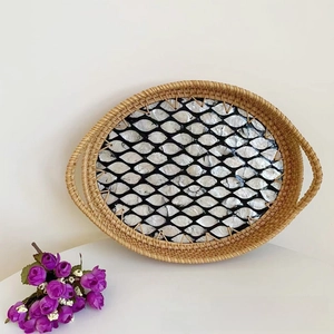 Detailed top view of handmade oval rattan tray with shell inlay and woven side handles