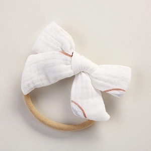 Détail du bandeau bébé avec nœud en mousseline de coton blanc et imprimé arc-en-ciel