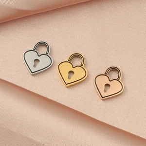 Three heart lock pendants in silver, gold and rose gold on pink silk fabric