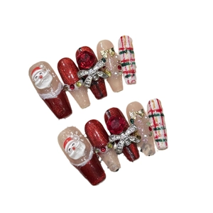 Handmade red Christmas press-on nails featuring 3D Santa Claus and glittery bow designs