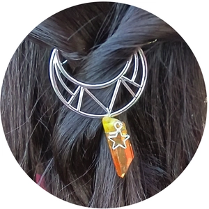Hollow crescent moon hair clip with orange crystal pendant on dark hair
