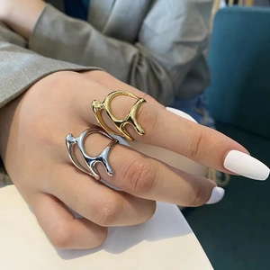 Close-up of trendy gold and silver irregular lava liquid rings worn on hand
