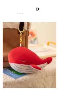 Detail of red and white plush whale keychain with gold metal clasp on a brown bag