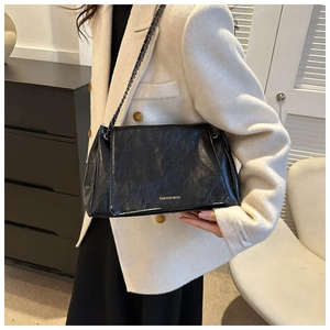Modern black texture leather underarm bag with gold chain strap on a model shoulder