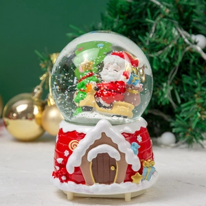 Detail of Christmas snow globe with Santa on motorcycle and gingerbread house base