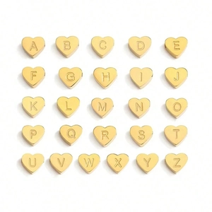 Detail of 26 gold heart-shaped metal beads featuring engraved letters A to Z for jewelry