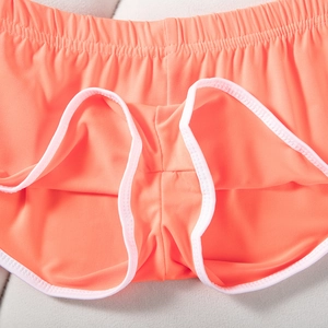 Detail der korallenorangen Sportshorts mit elastischem Bund und Strickstruktur