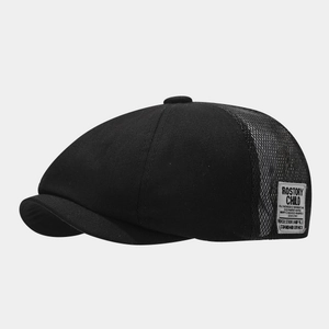 Detail view of the black newsboy hat featuring breathable mesh patchwork and a vintage side label