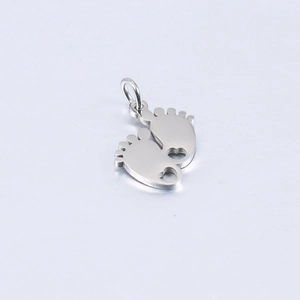 Macro detail of silver baby feet charm with heart cutout and mirror polished finish
