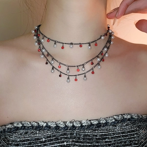 Detail of gothic multi-layer choker necklace featuring pearls and red crystals on dark metal