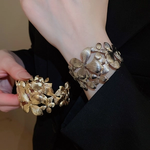 Détail de la texture des pétales superposés sur le bracelet ouvert doré et argenté