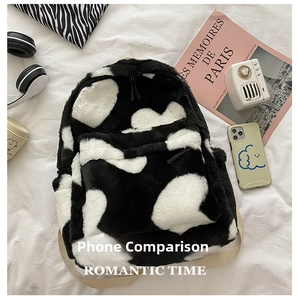 Detailed top view of a fuzzy cow print backpack with lifestyle gadgets for size comparison