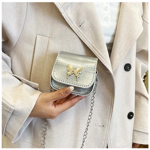 Detailed macro view of the silver mini bag featuring a 3D metal butterfly and chain strap