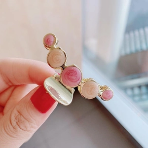 Detail of gold metal hair claw clip with pink and beige swirl pattern pearl accents