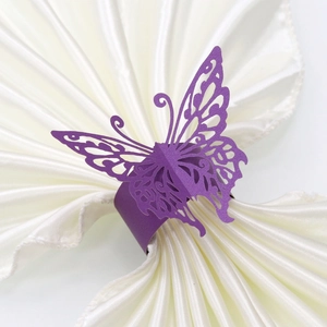 Close-up of purple laser-cut butterfly napkin ring on a white satin fabric background