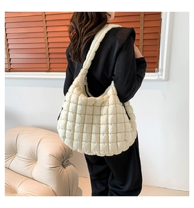 Close-up of cream quilted puff shoulder bag on model with soft lighting detail