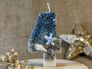 Macro detail of ocean-themed number 4 candle with blue glitter, starfish and shells