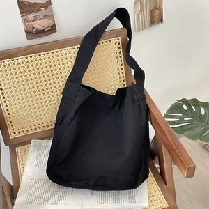 Dettaglio della borsa a tracolla in tela nera di grande capacità su una sedia vintage