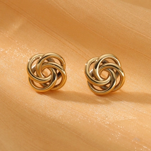 Macro shot of gold-toned spiral earrings with textured swirl design on satin fabric