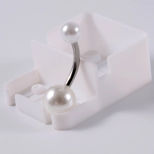 Détail macro d'un piercing de nombril courbé avec deux perles blanches polies