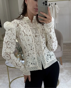 Detalle de blusa blanca de encaje con cuello alto y botones chinos tradicionales