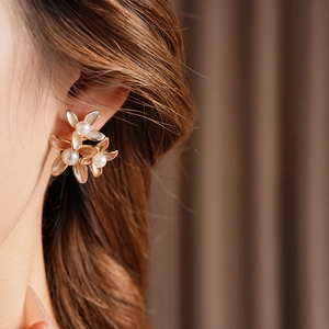 Close-up of elegant flower earrings with white pearls and gold-plated floral petals