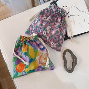 Detail of oil painting floral drawstring pouches with cotton cords on white table