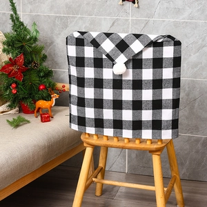 Detail of Christmas chair cover with black and white plaid pattern and white fuzzy pom pom