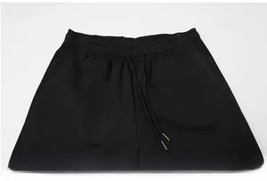 Dettaglio dei pantaloni in pile neri con elastico in vita e coulisse con punte in metallo