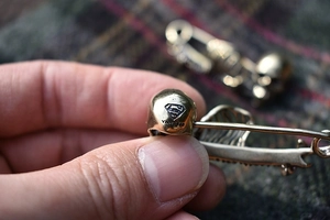 Close-up of gothic skull safety pin with engraved Superman logo and YNR 925 mark