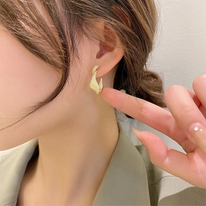 Close-up of elegant golden twisted geometric earrings on model for a stylish look