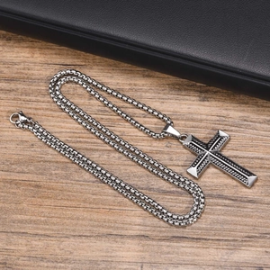 Detailed view of silver stainless steel twisted rope cross pendant on a textured wood surface