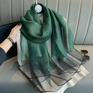 Detail of silk scarf with gold thread gradients draped over a white sweater