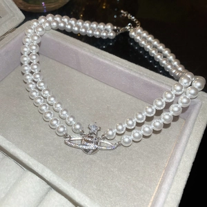 Detail of double-layer pearl necklace with zircon-encrusted silver Saturn pendant