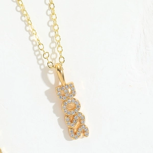 Close-up of gold plated BOSS letter pendant necklace with sparkling pavé zircons