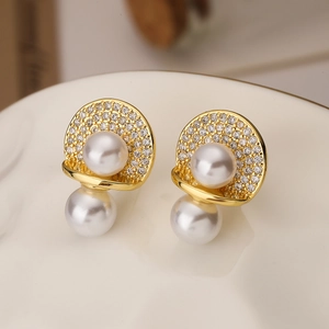 Elegant gold earrings with micro-paved zircons and white pearls on white plate