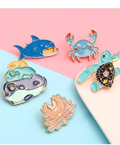 Close-up of alloy enamel pins featuring shark, crab, turtle and rabbit animal designs