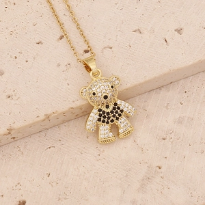 Macro view of gold teddy bear pendant with clear and black zircons on stone surface