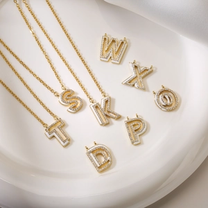 Elegant gold alphabet necklaces with white enamel and sparkling zircon on white silk