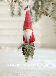 Detail of Christmas gnome ornament with red felt hat, white beard and natural pine cone base