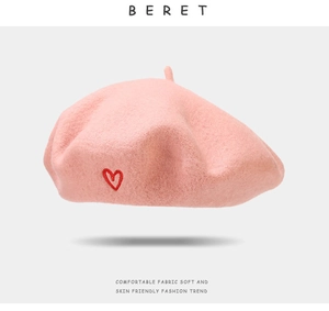 Detailed close-up of pink wool beret featuring a delicate red heart embroidery detail